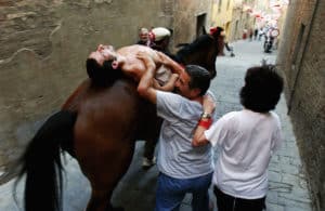 Man carried by a horse through anarrow streets of Siena