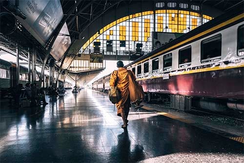 A monk in a yellow robe walks to his train