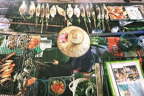 A woman is selling fresh fish and vegetables from her tiny stall