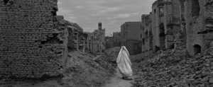 A woman wrapped in white walks through her destroyed home town