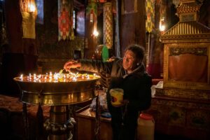 An elderly man lights candles in a Tibetian monastery