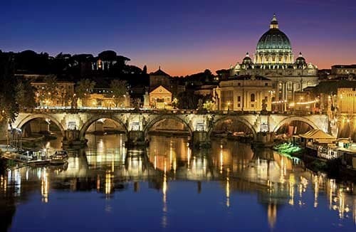 Illuminated buildings of Rome reflecting in river Tiber