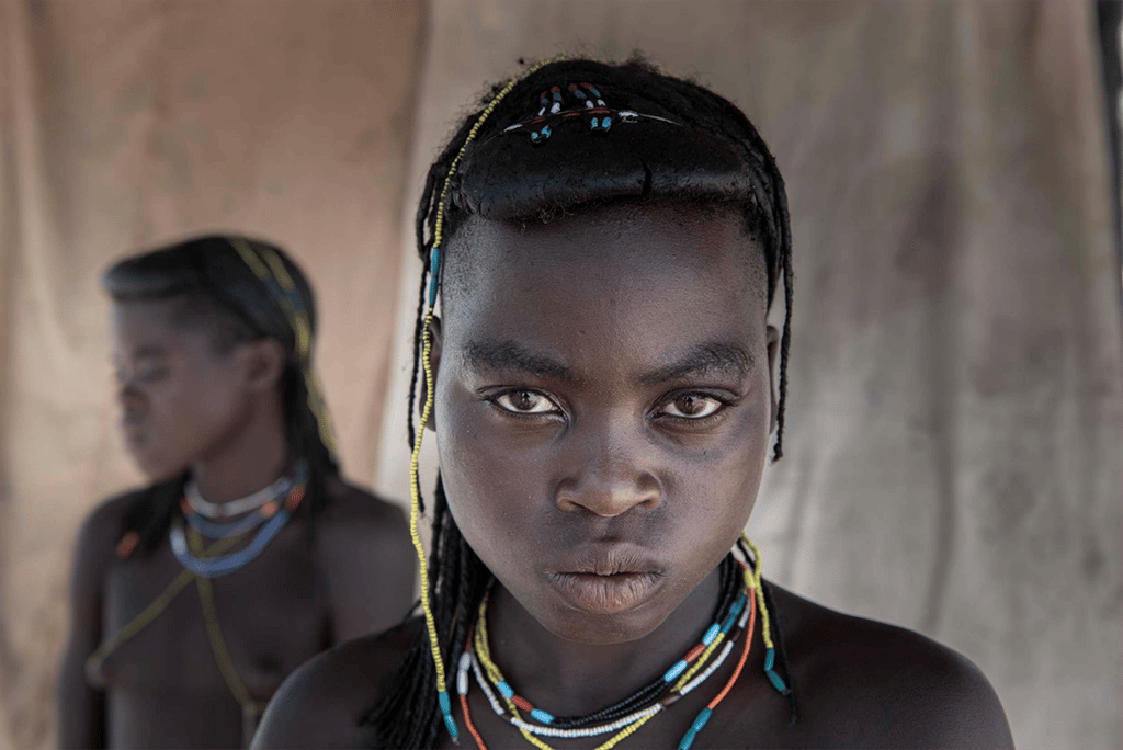 A portrait of a Himba young girl with braised hair wearing colourful necklaces
