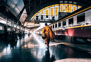A monk is spotting walking next to an old train in the Bangkok's main train station
