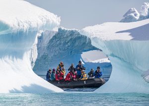 a group of photographers on a zodiac crusing in front of icebergs