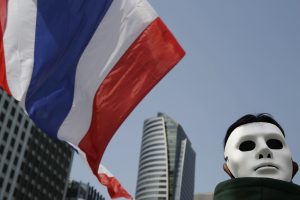 Thailand flag next to a man in white mask