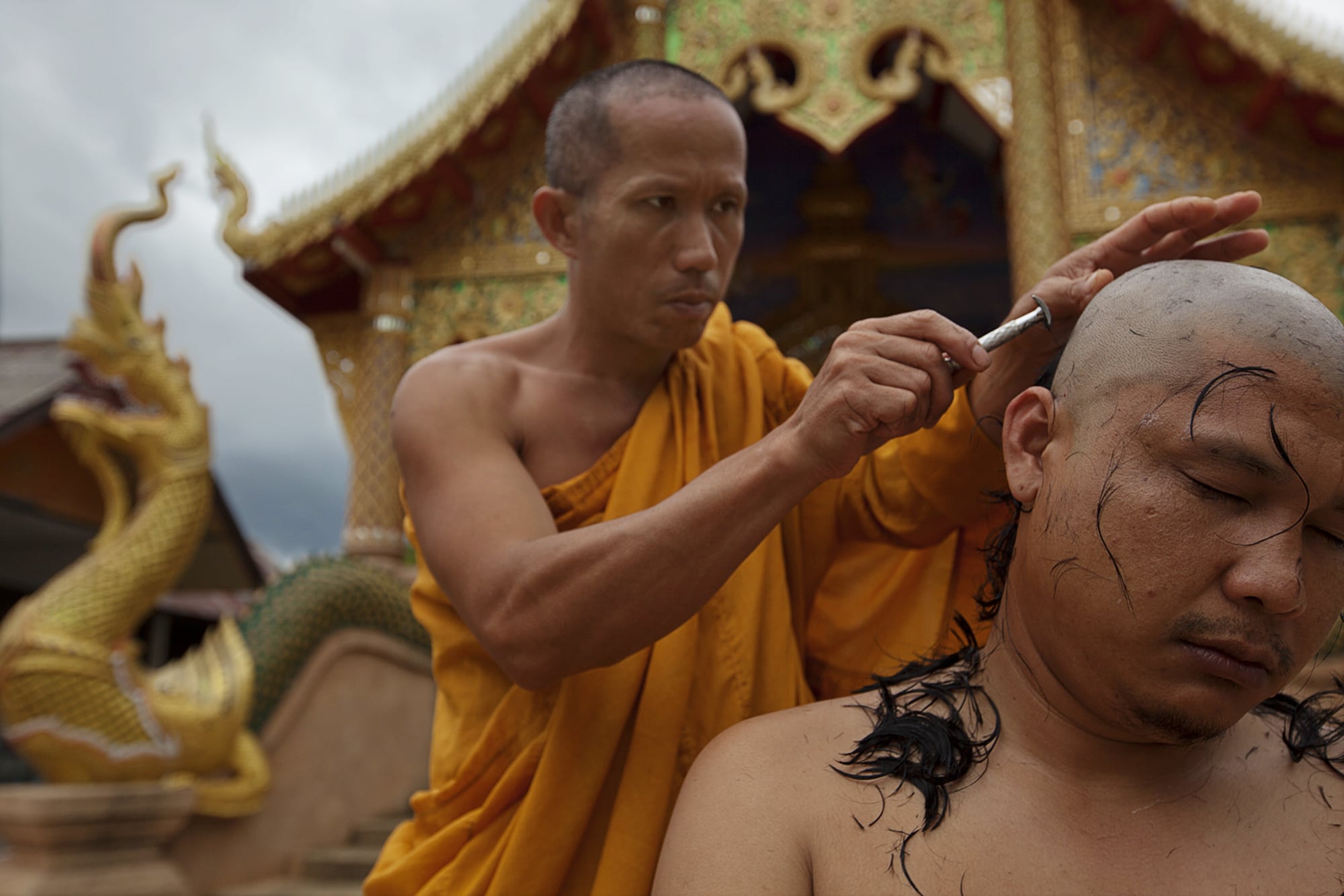 A monk shaving another monk's hair